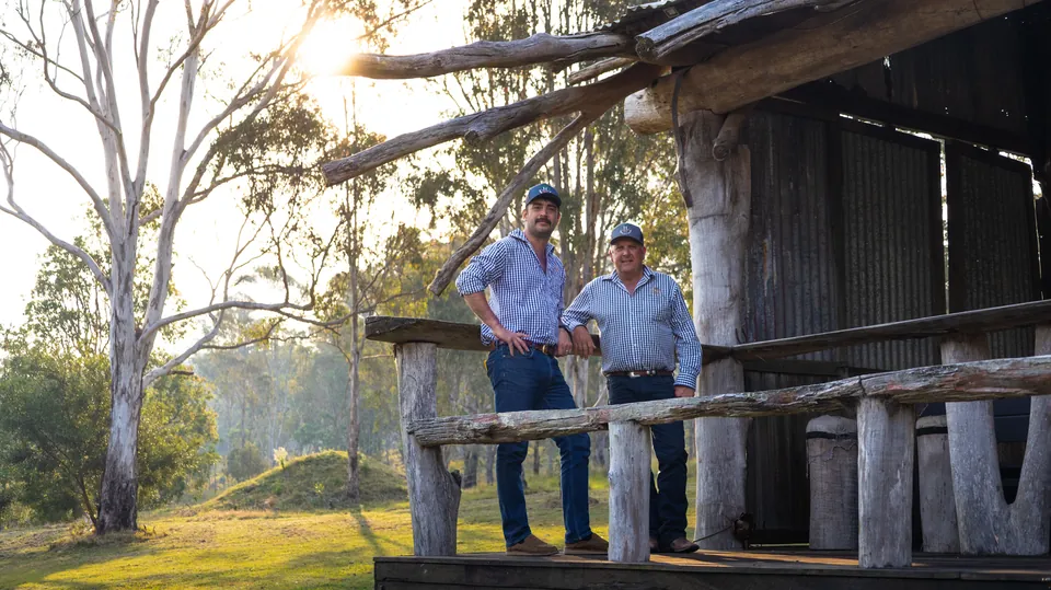 Two business owners photographed under a machinery shed on a rural property