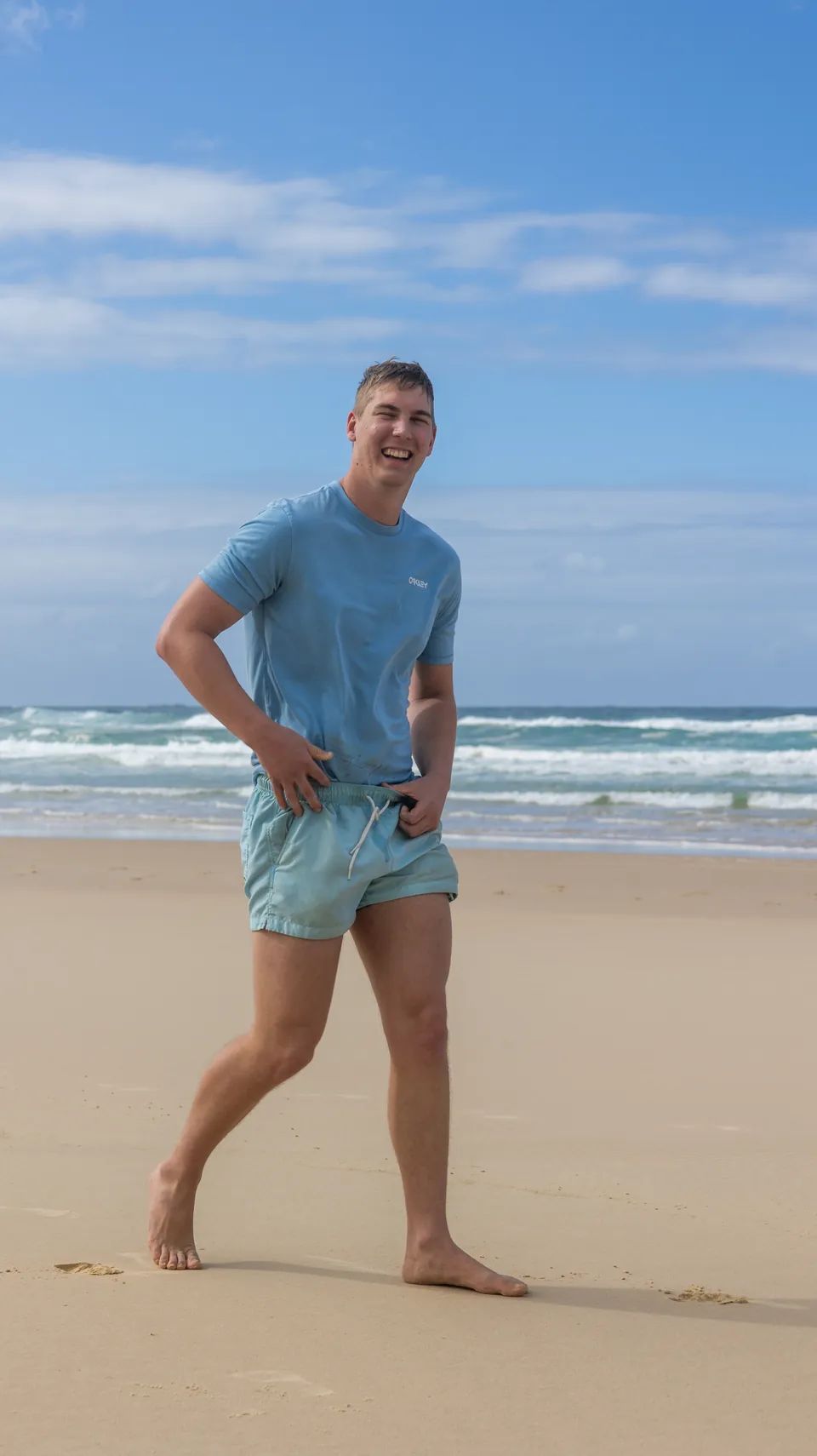 Man walking along a wide surf beach