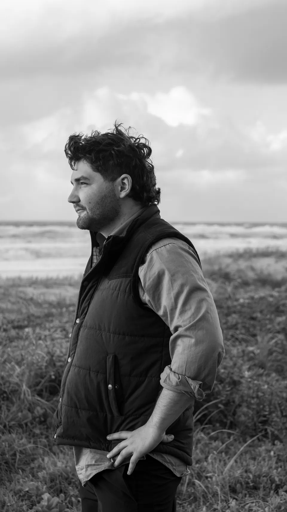 Black and white environmental portrait of a man in open country